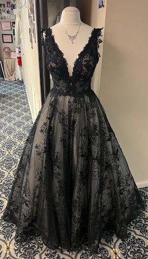 A black dress is on a mannequin in a room.