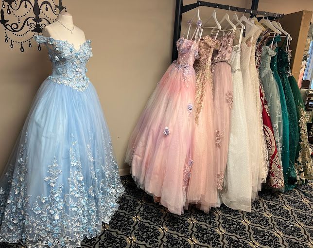 A bunch of dresses are hanging on a rack in a room.