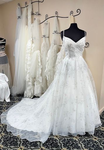 A white wedding dress is on a mannequin in a bridal shop.