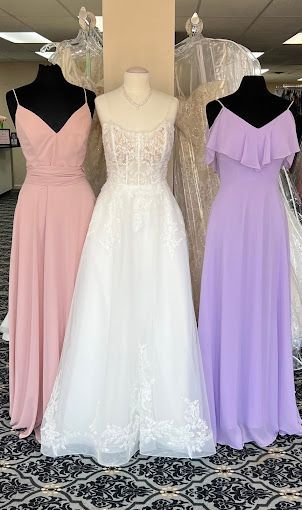 Three dresses are displayed on mannequins in a store.