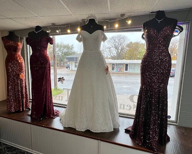 A row of dresses are displayed on a window sill in a store.