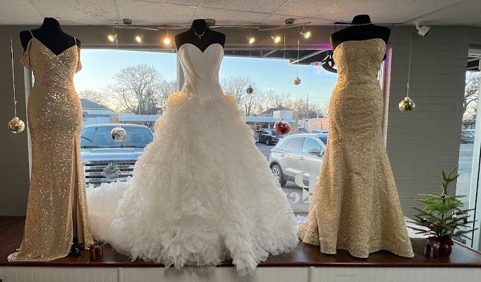 Three wedding dresses are displayed on mannequins in a store window.