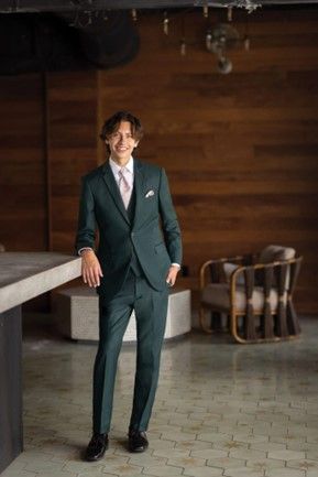 A man in a green suit and tie is standing in a room - Salina, KS - Princess & Penguin Formalwear