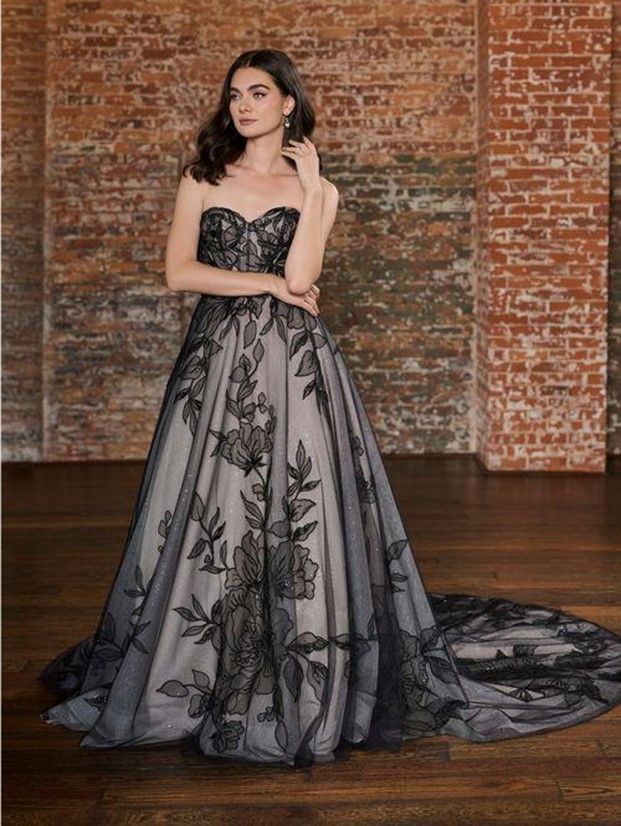 A woman in a black and white dress is standing in front of a brick wall - Salina, KS - Princess & Penguin Formalwear