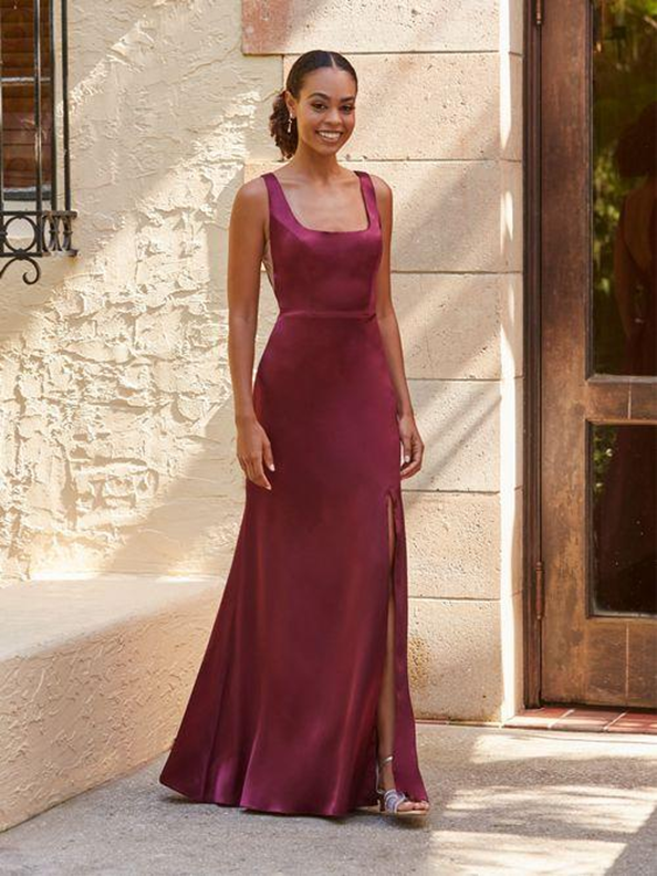 A woman is wearing a burgundy bridesmaid dress and standing in front of a building - Salina, KS - Princess & Penguin Formalwear