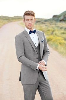 A man in a suit and bow tie is standing on a dirt road - Salina, KS - Princess & Penguin Formalwear
