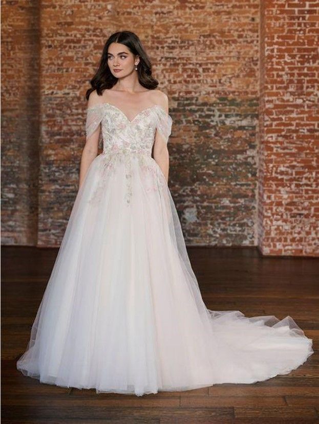 A woman in a wedding dress is standing in front of a brick wall - Salina, KS - Princess & Penguin Formalwear