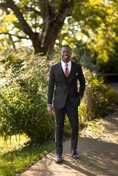 A man in a suit and tie is standing in front of a tree - Salina, KS - Princess & Penguin Formalwear