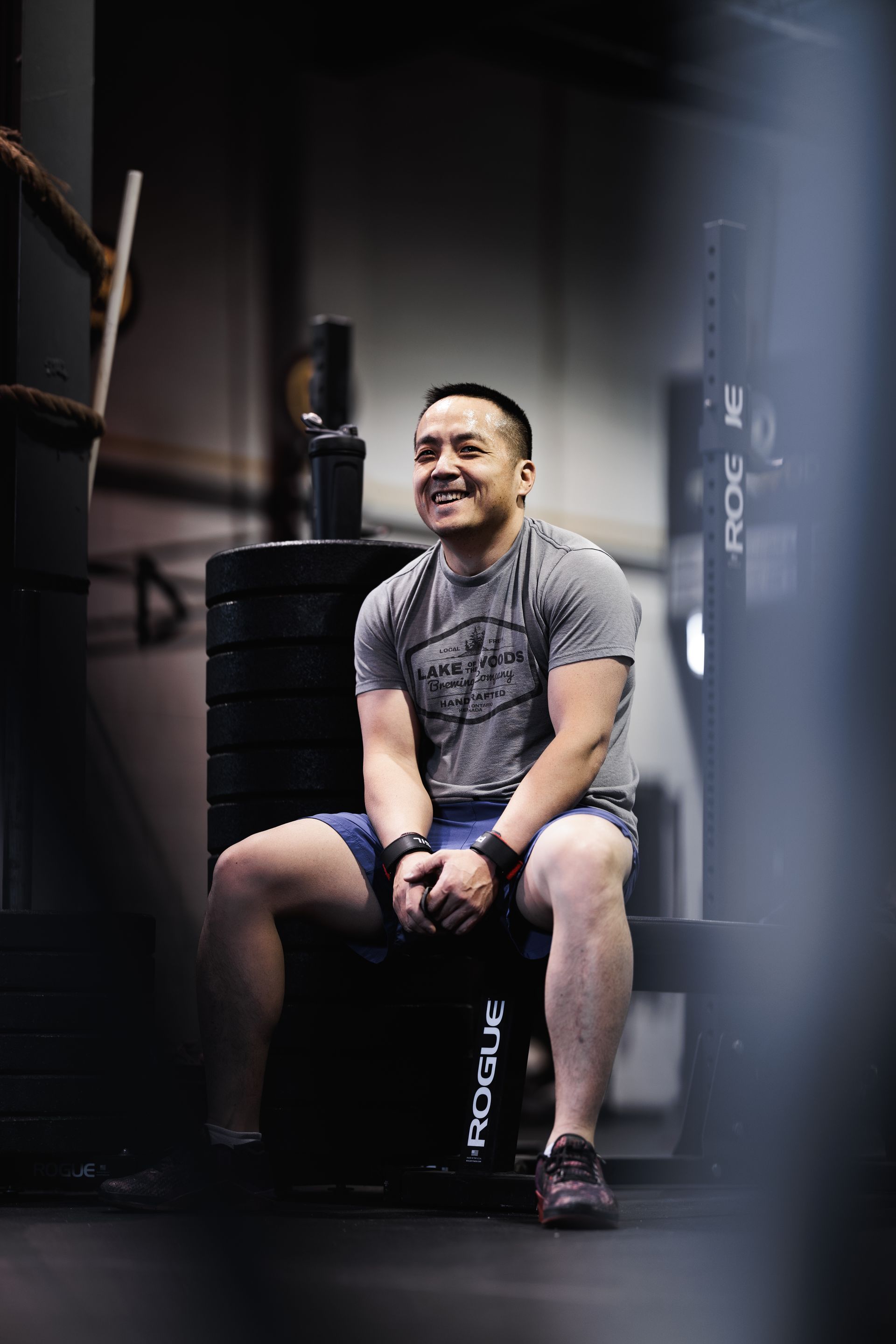 Man sitting on a weight stack, smiling in a gym.