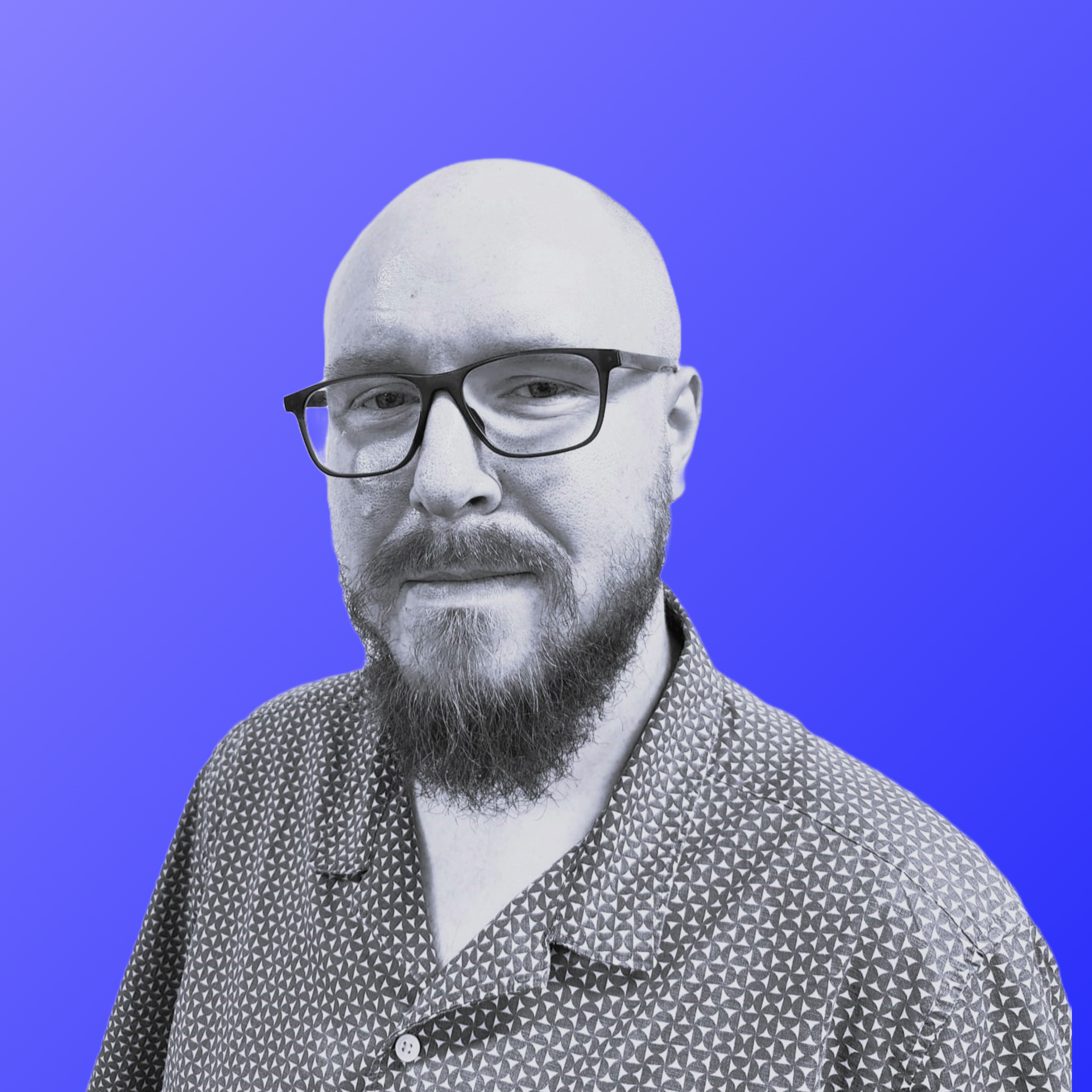 A man with a beard is wearing a green shirt and standing in front of a blue background.