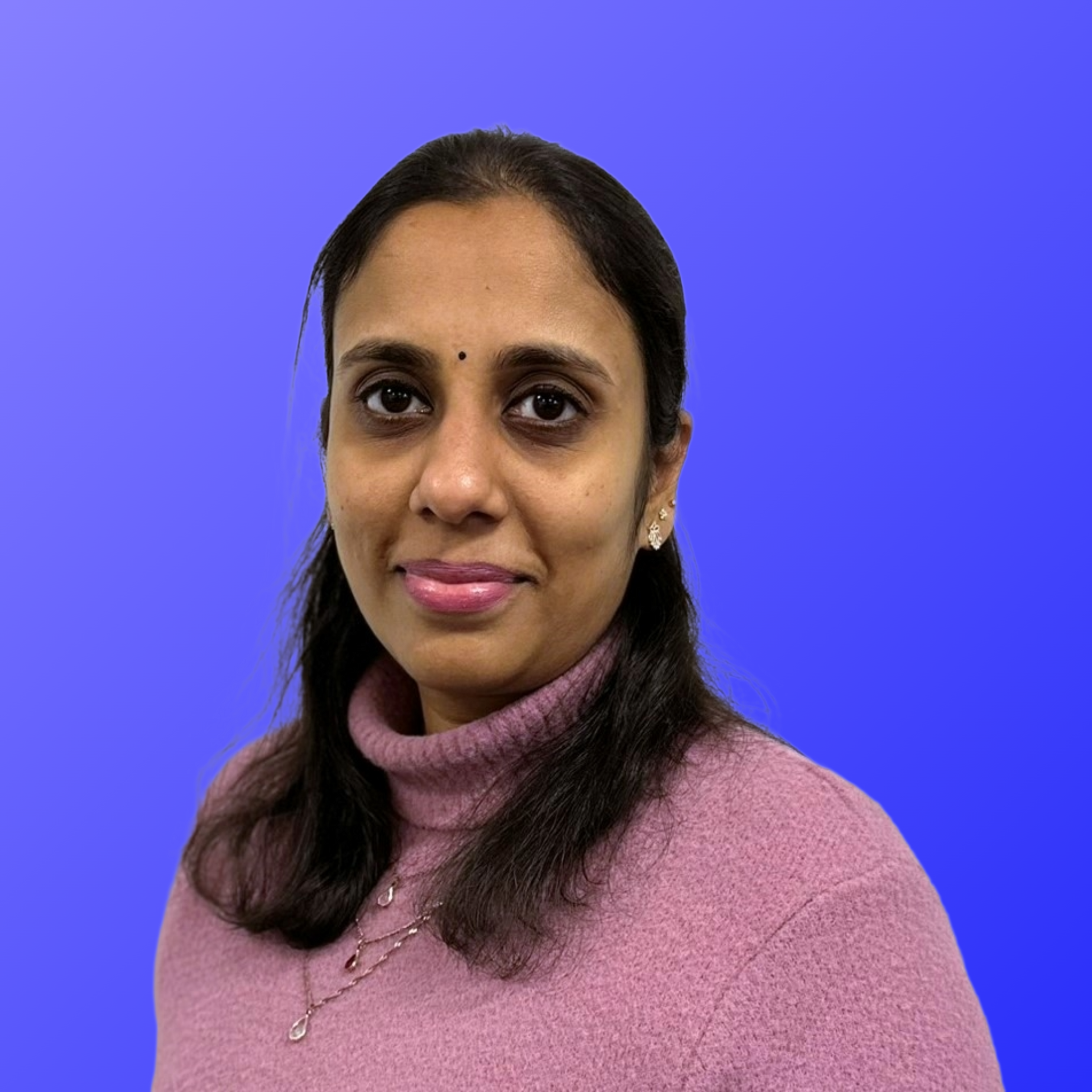 A woman is standing in front of a blue background.