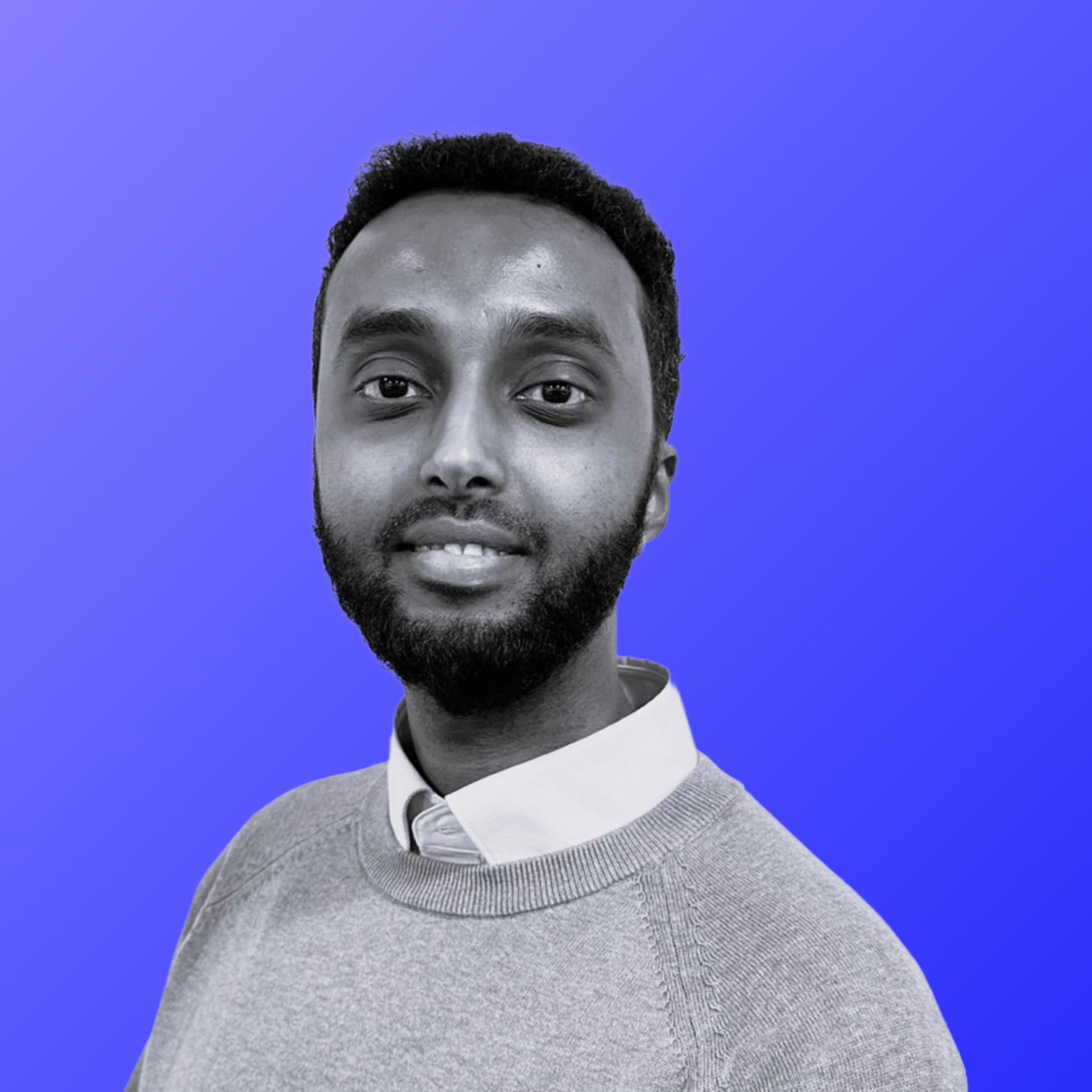 A man with a beard is wearing a shirt and jumper.