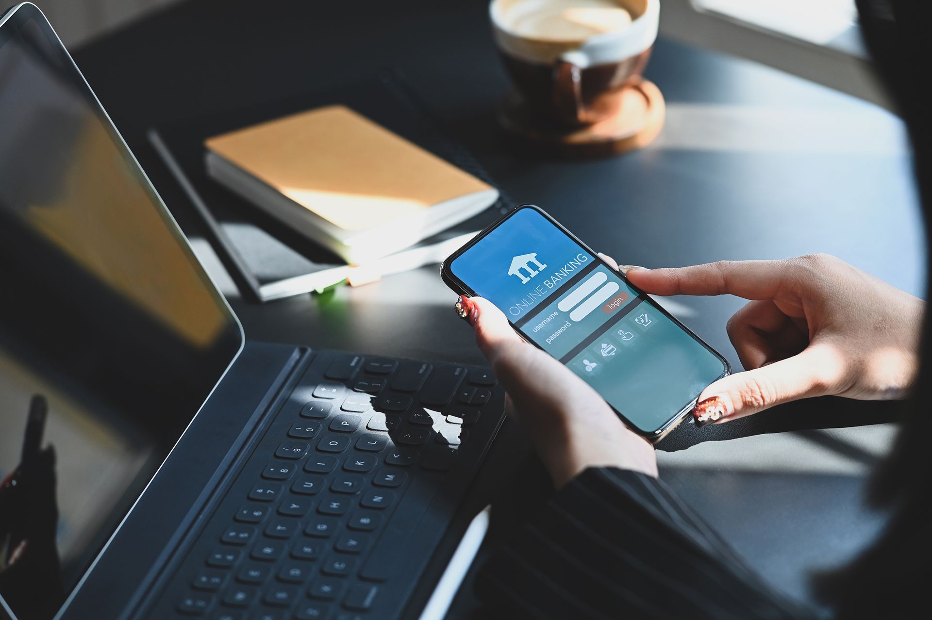 A person is holding a cell phone in front of a laptop.