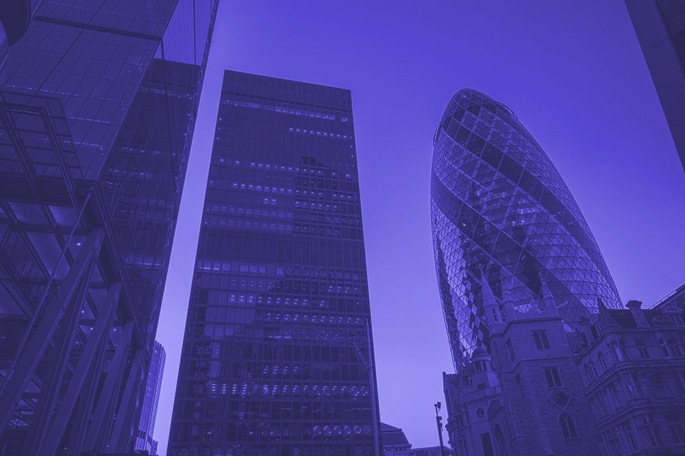 Looking up at a group of tall buildings in a city at night.