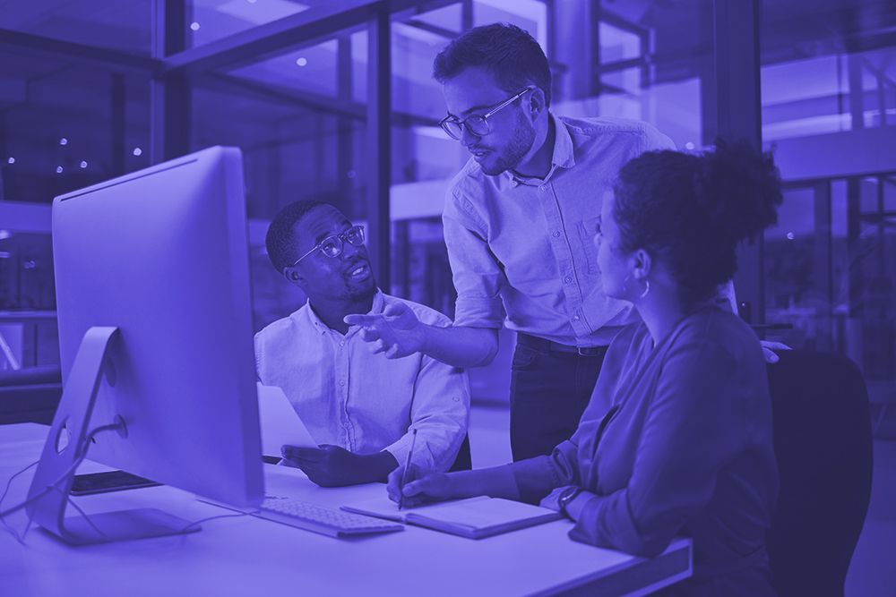 A group of people are sitting at a desk looking at a computer screen.