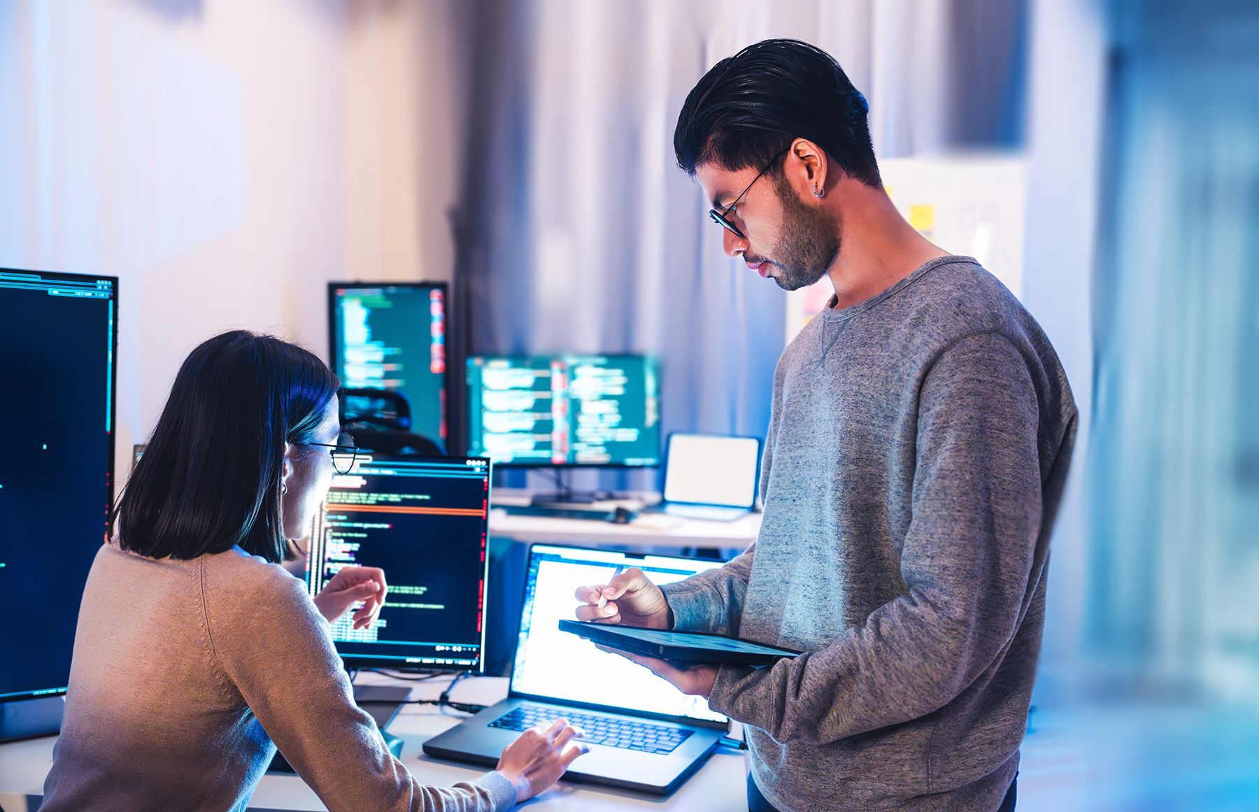 A man and a woman are working on a computer in an office.