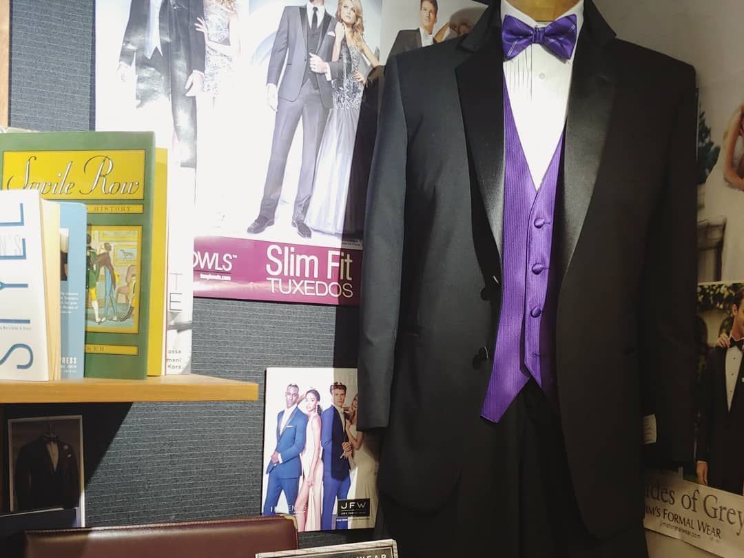 A black tuxedo with a purple vest and bow tie