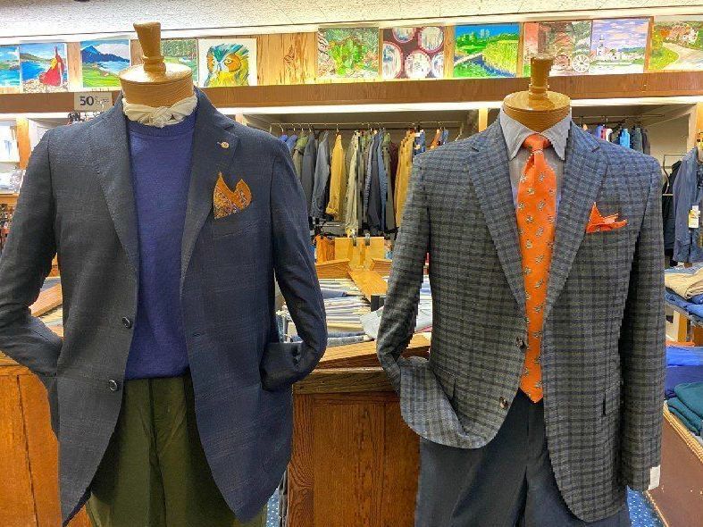 Two mannequins wearing suits and ties are standing next to each other in a store.