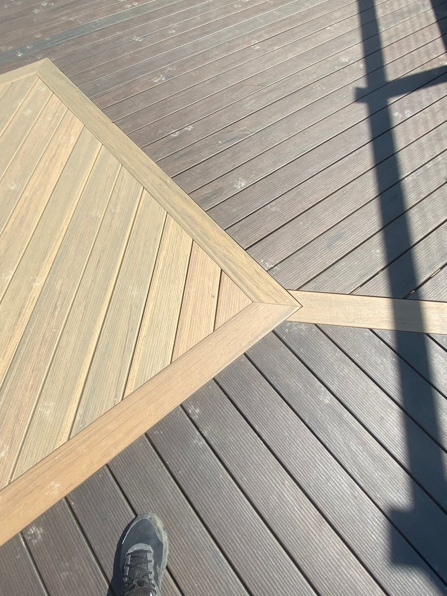 Wooden deck walkway with a triangular planter and a shoe visible at the bottom edge.