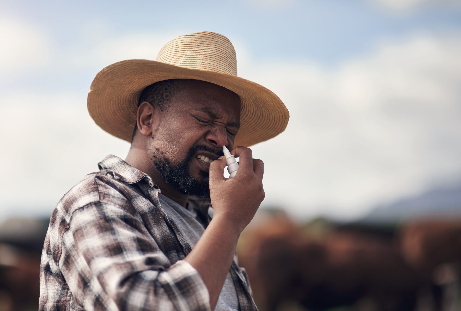 A man in a cowboy hat is dealing with occupational rhinitis.