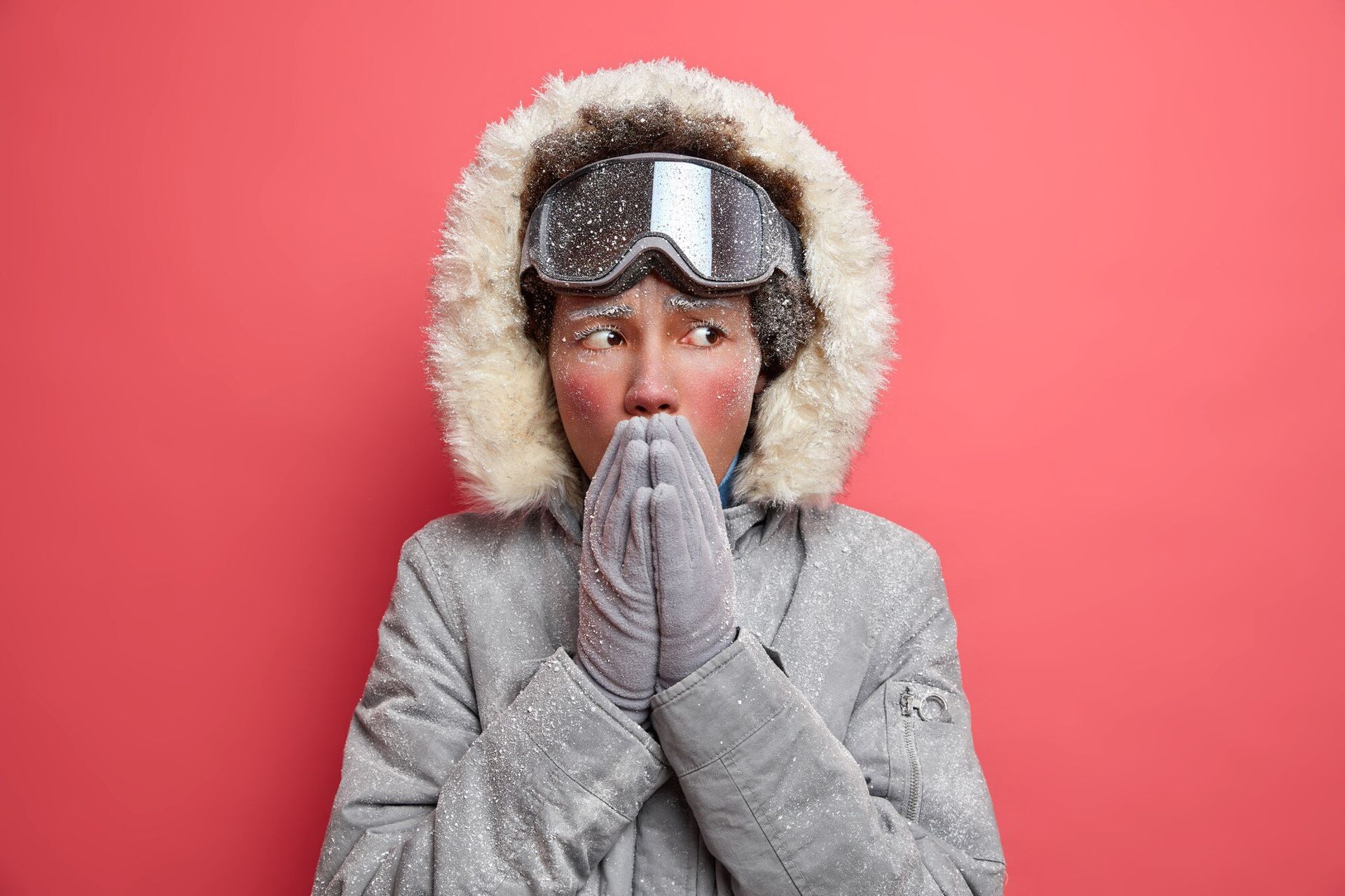 A person in winter clothes covers their mouth before sneezing, a common winter allergy symptom.