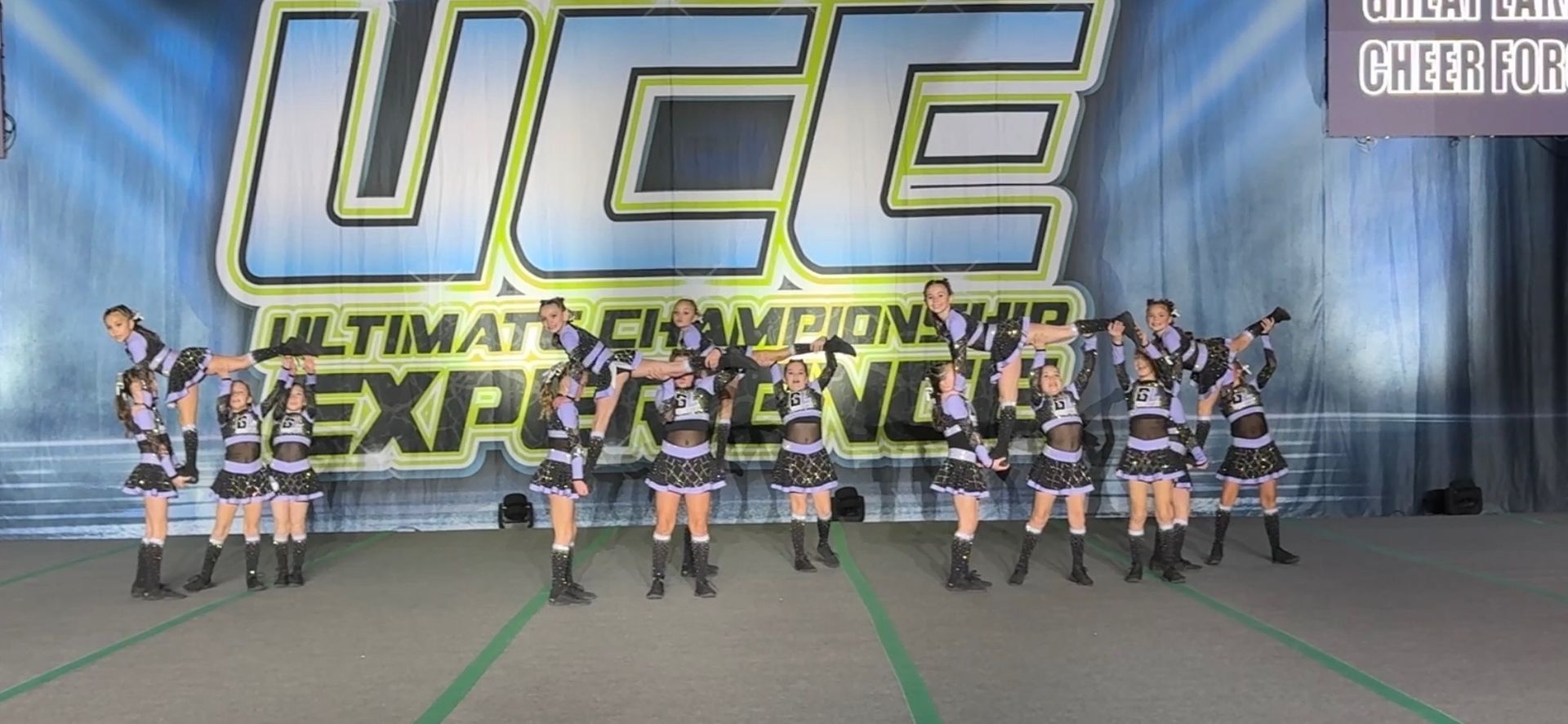 A group of cheerleaders are standing in front of a sign that says uce