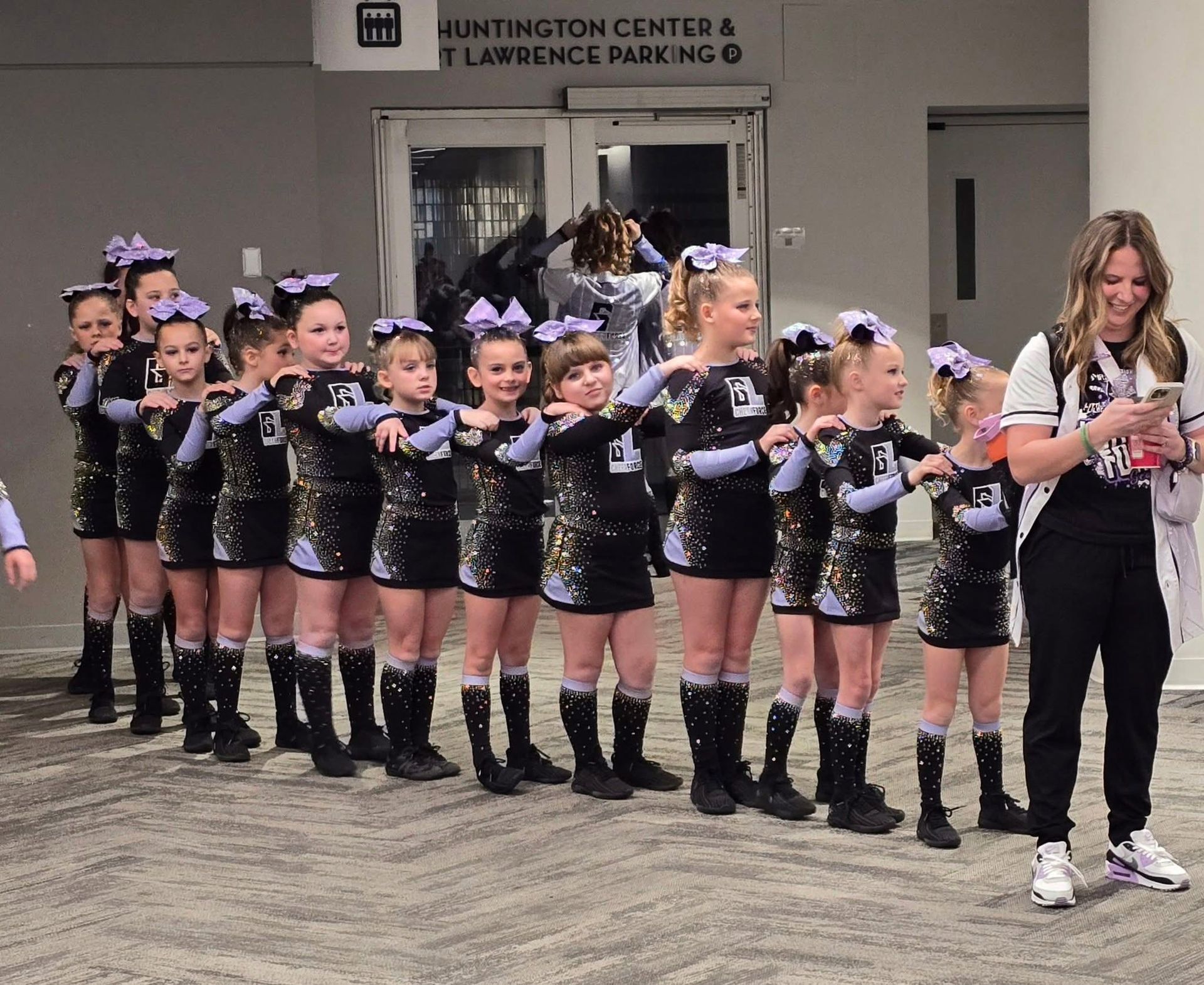 A group of cheerleaders are standing in front of a sign that says huntington center & lawrence parking