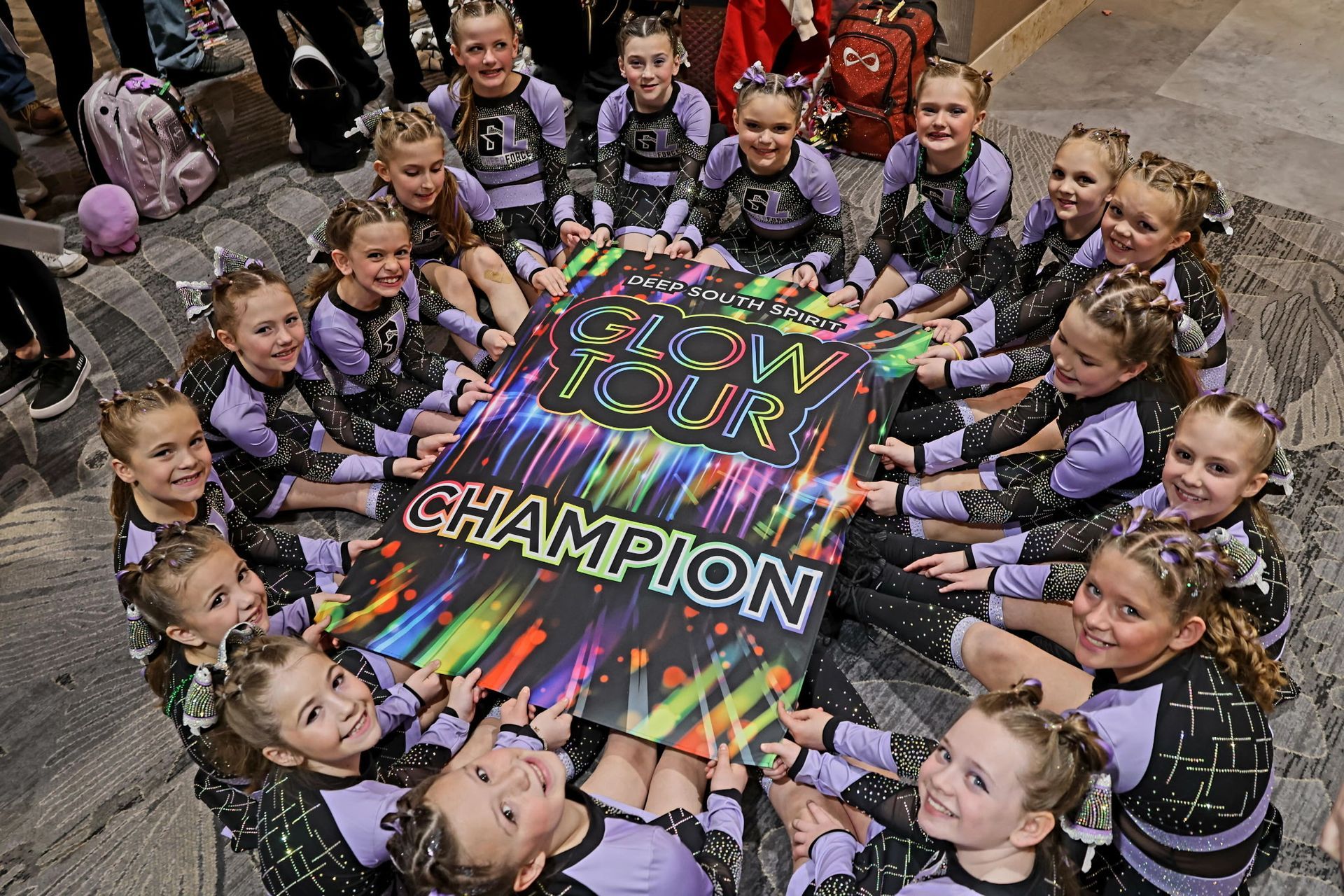 A group of cheerleaders are sitting around a sign that says champion.