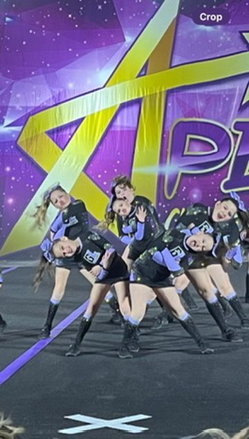 A group of cheerleaders are performing on a stage in front of a sign that says crop