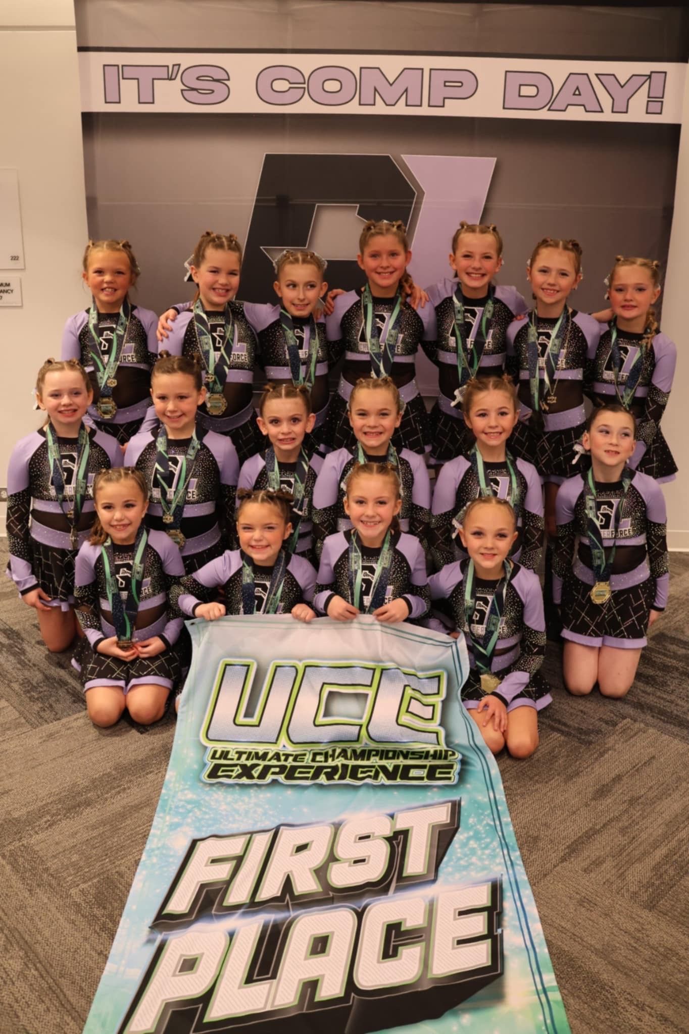 A group of young girls are posing for a picture with a cake that says first place.