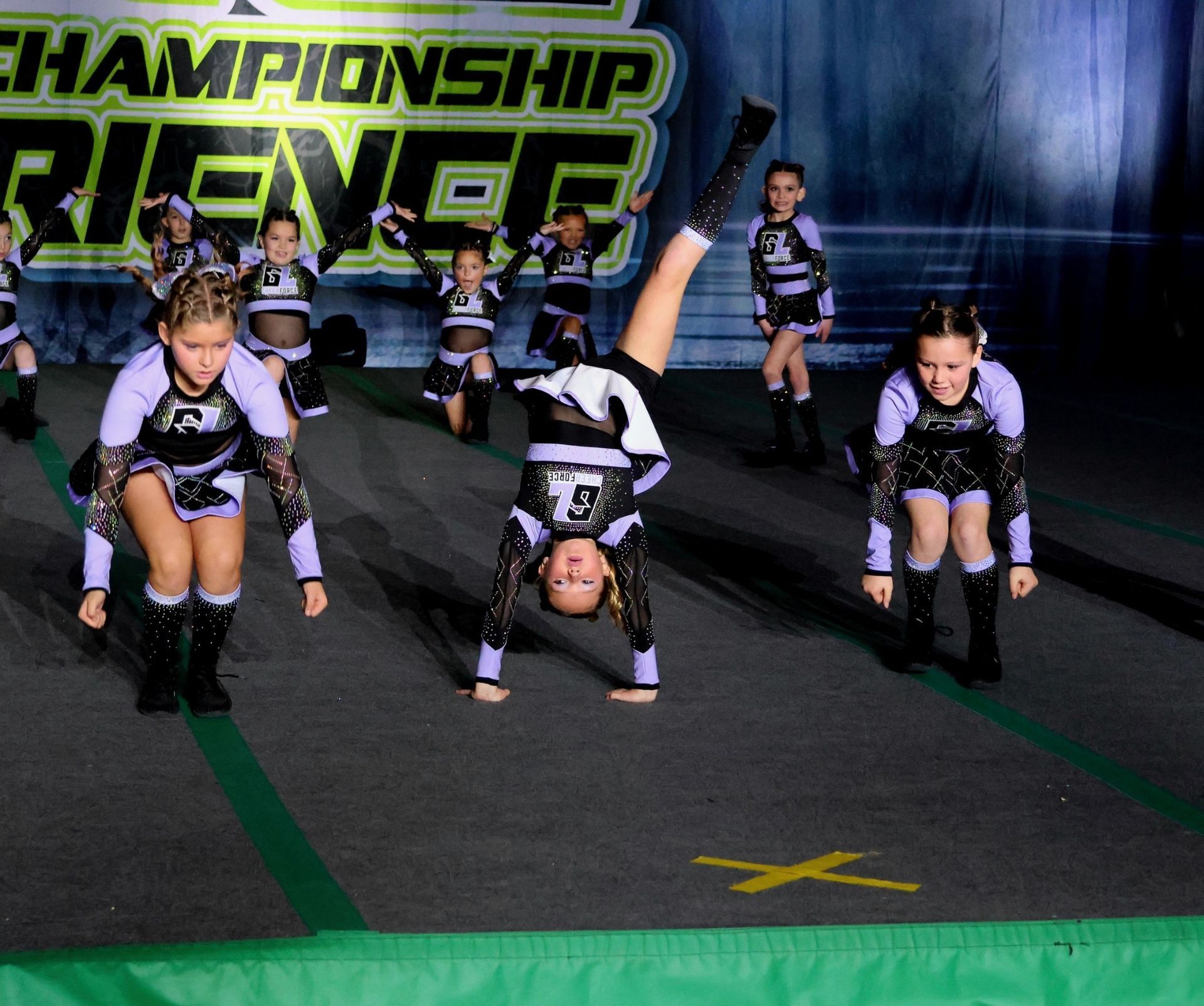 A group of cheerleaders are doing a handstand in front of a championship sign
