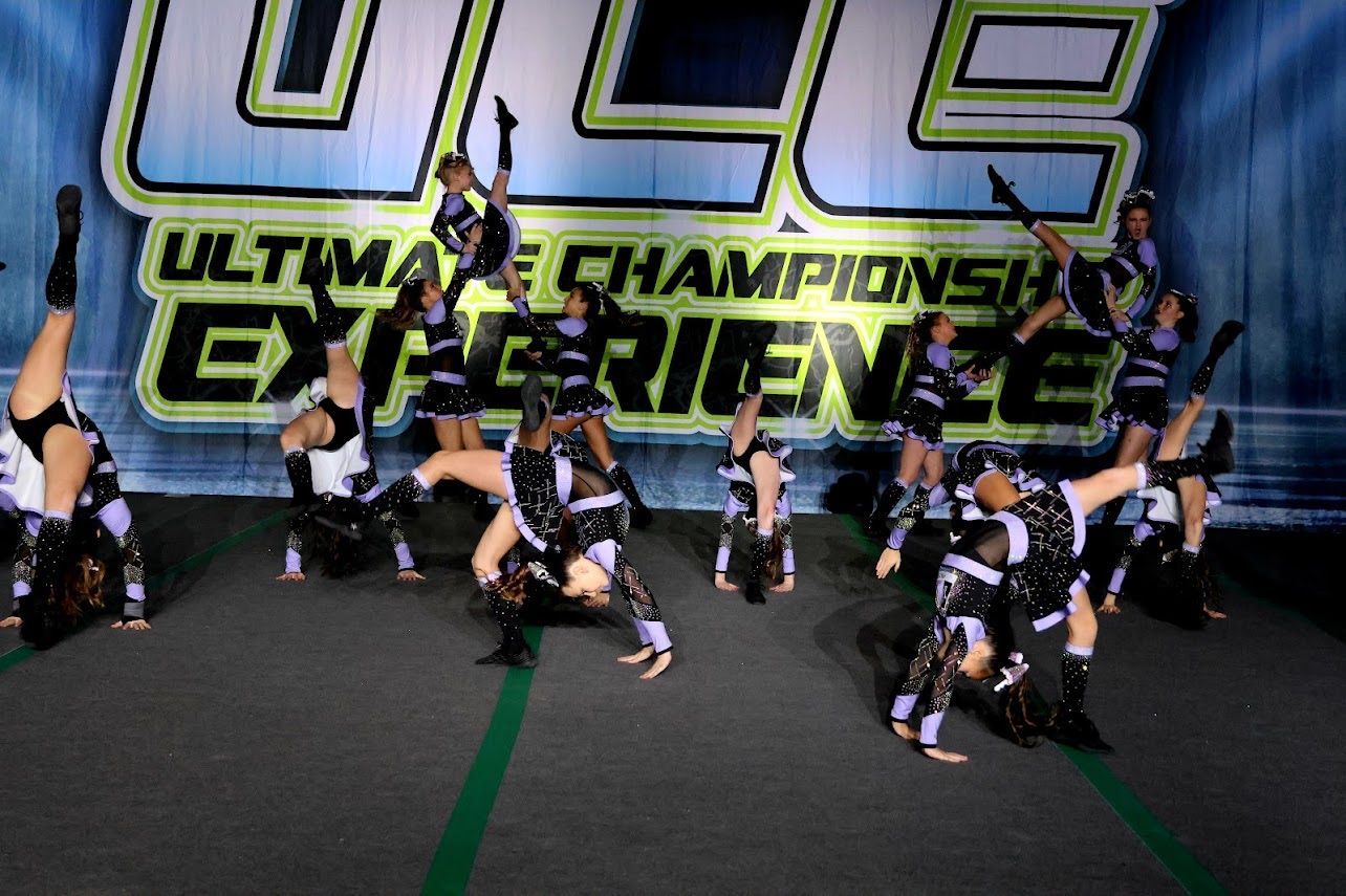 A group of cheerleaders are performing in front of a banner that says ultimate championship experience
