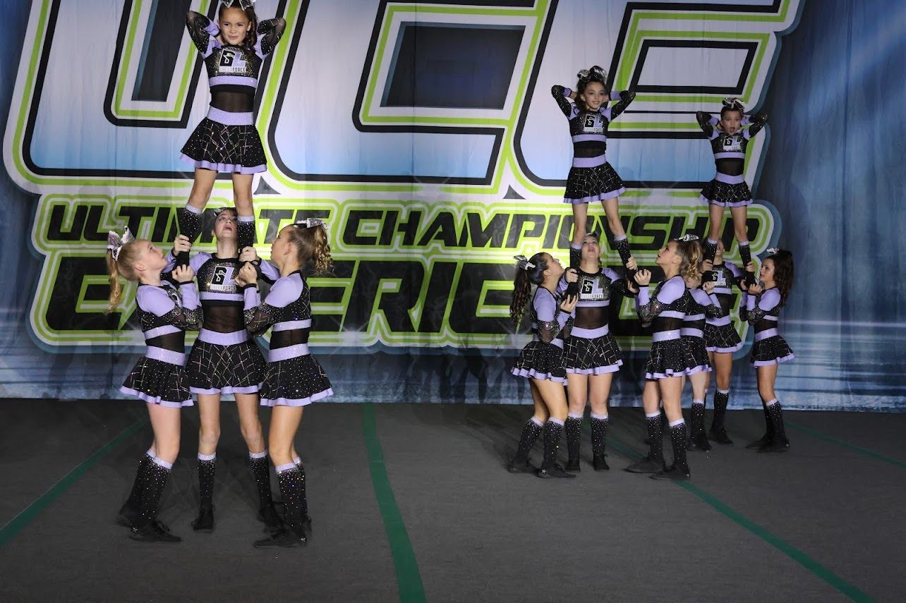 A group of cheerleaders are performing in front of a sign that says ultimate championship experience.
