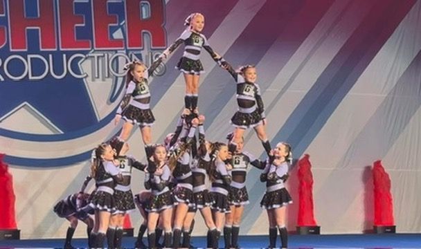 A group of cheerleaders are doing a pyramid on a stage.