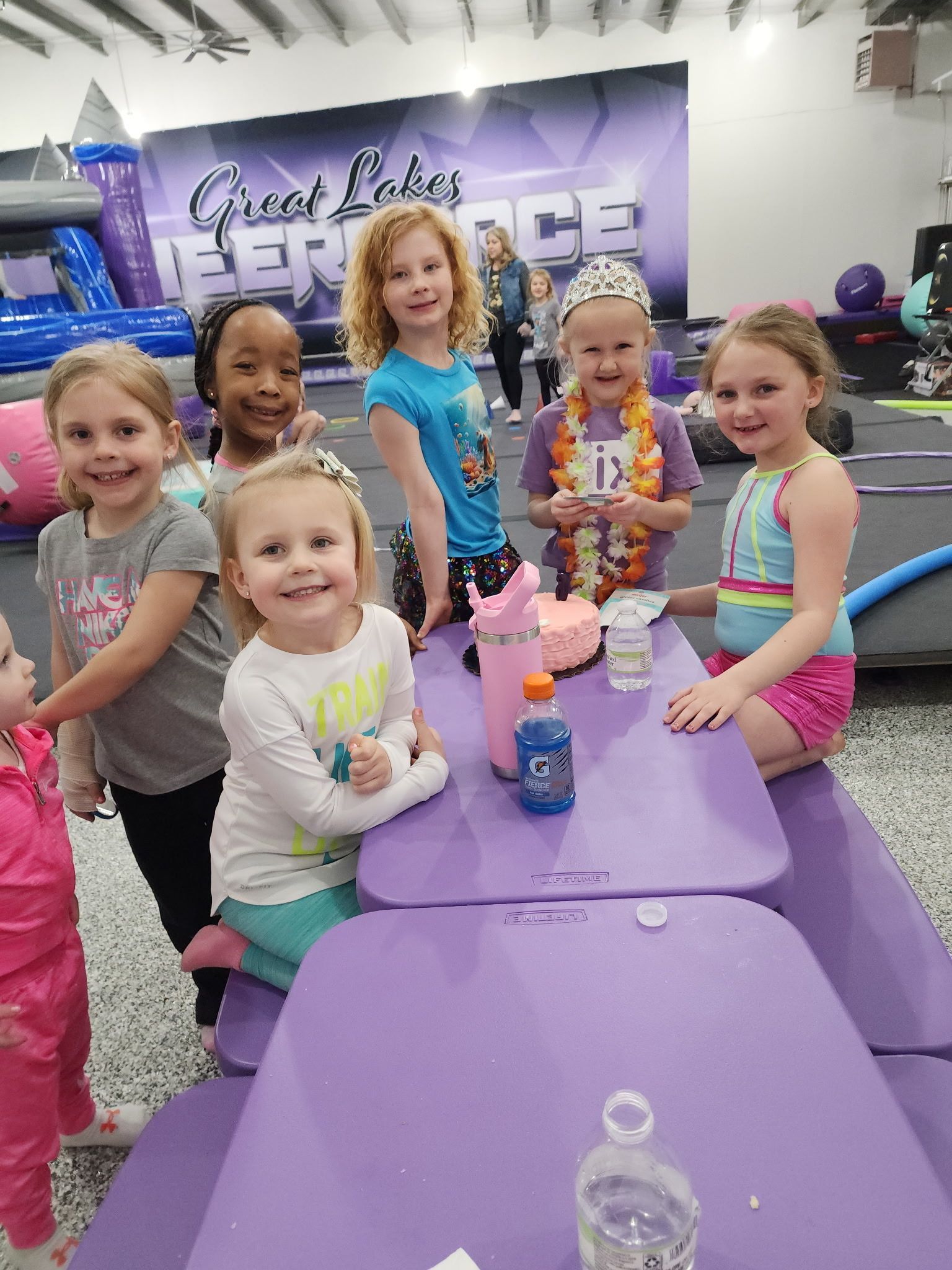 A group of young girls are sitting at a table in a gym.