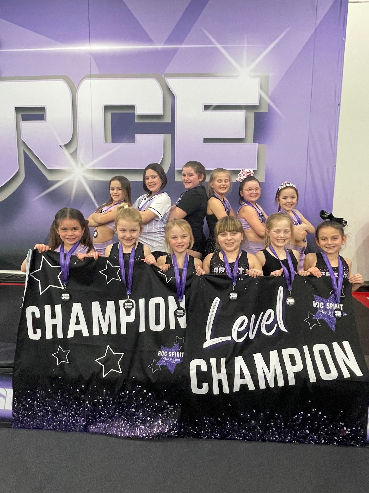 A group of young girls are posing for a picture with a banner that says champion level champion.