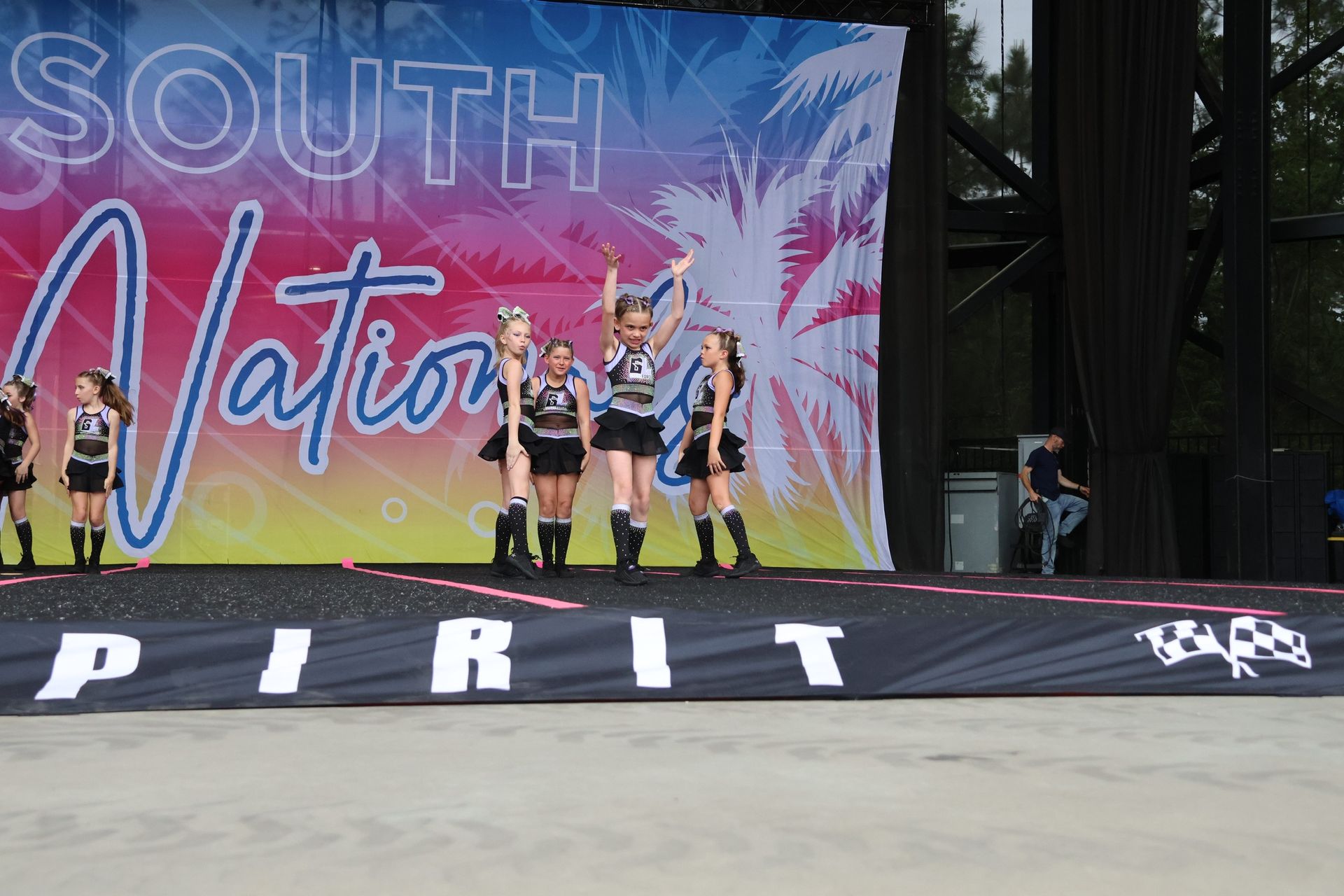 A group of cheerleaders are performing on a stage in front of a south nation banner.