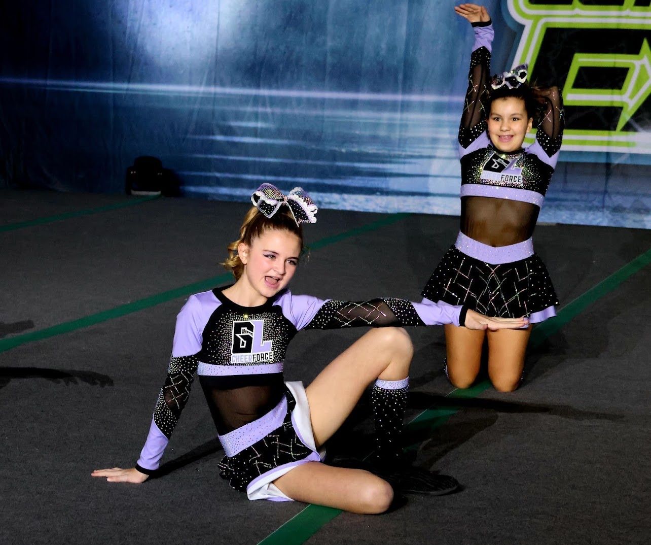 2 girls in black and purple GL uniforms cheering.