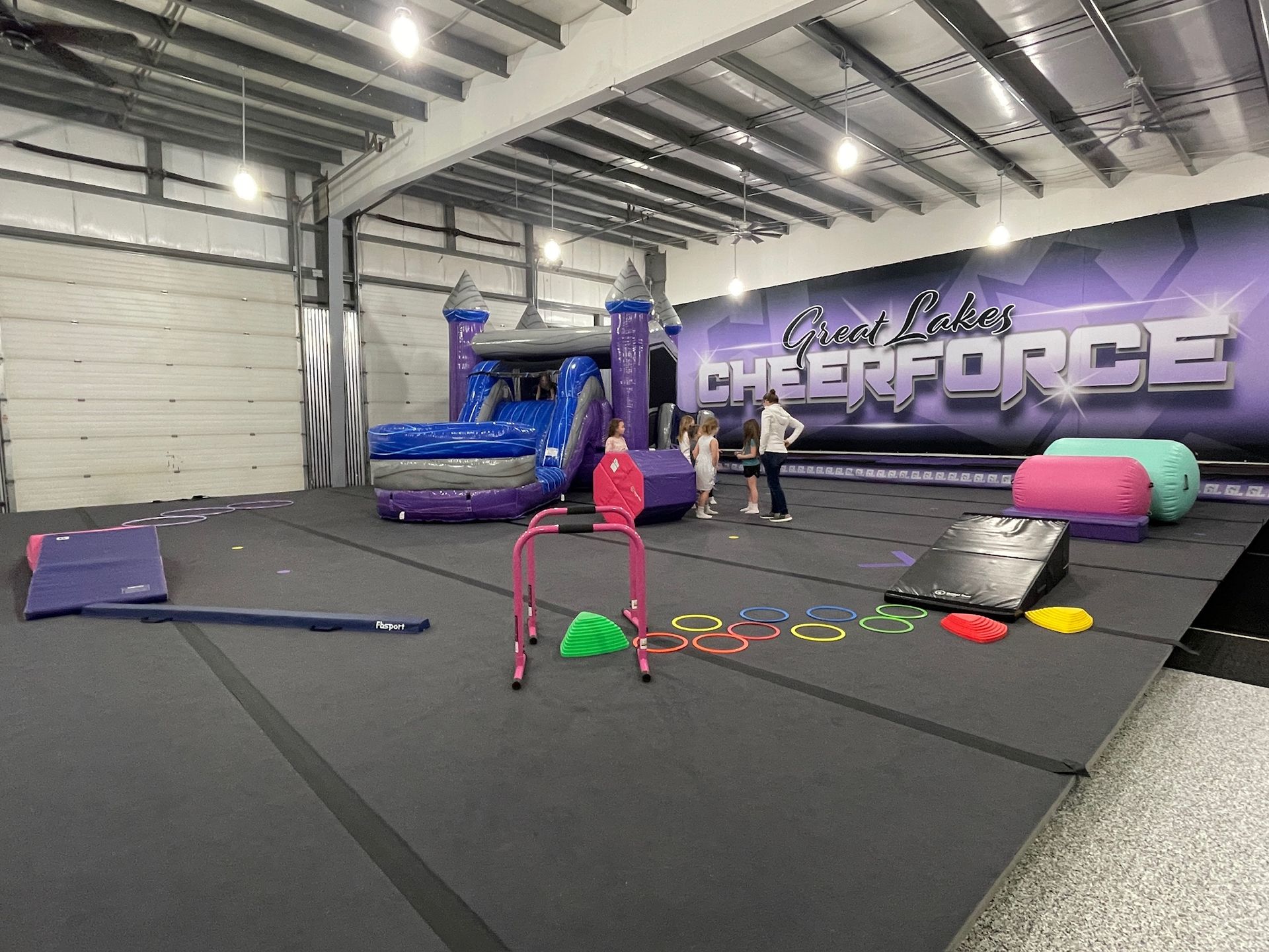 A large room with a bouncy house and a sign that says cheerforce.