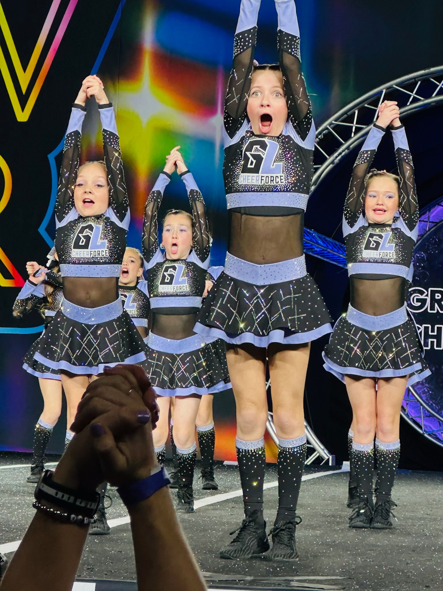 A group of cheerleaders are standing on a stage with their arms in the air.