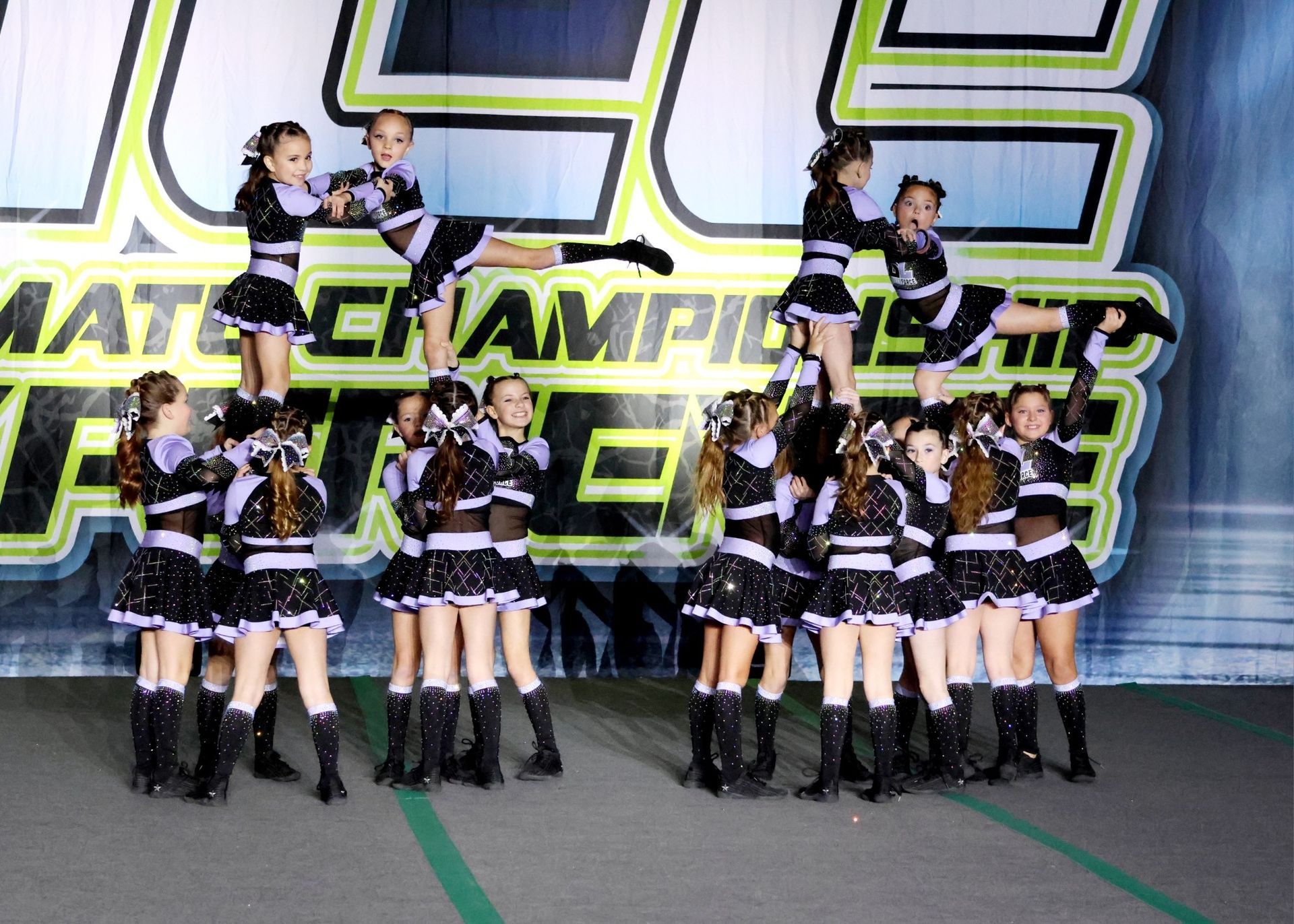 A group of cheerleaders are performing in front of a sign that says champions