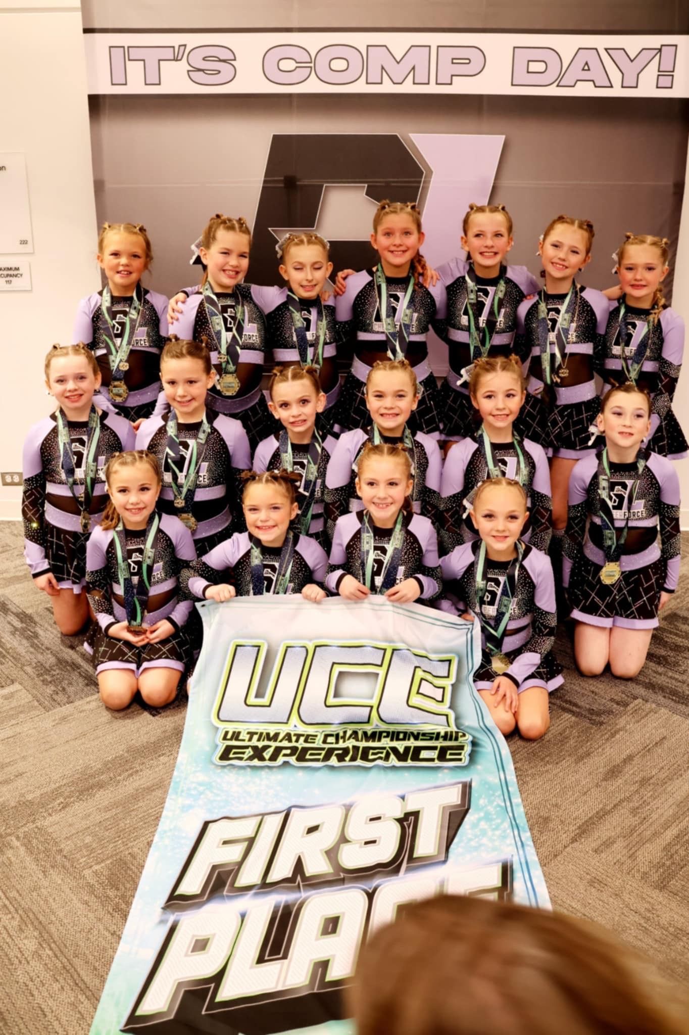 A group of cheerleaders are posing for a picture in front of a cake.
