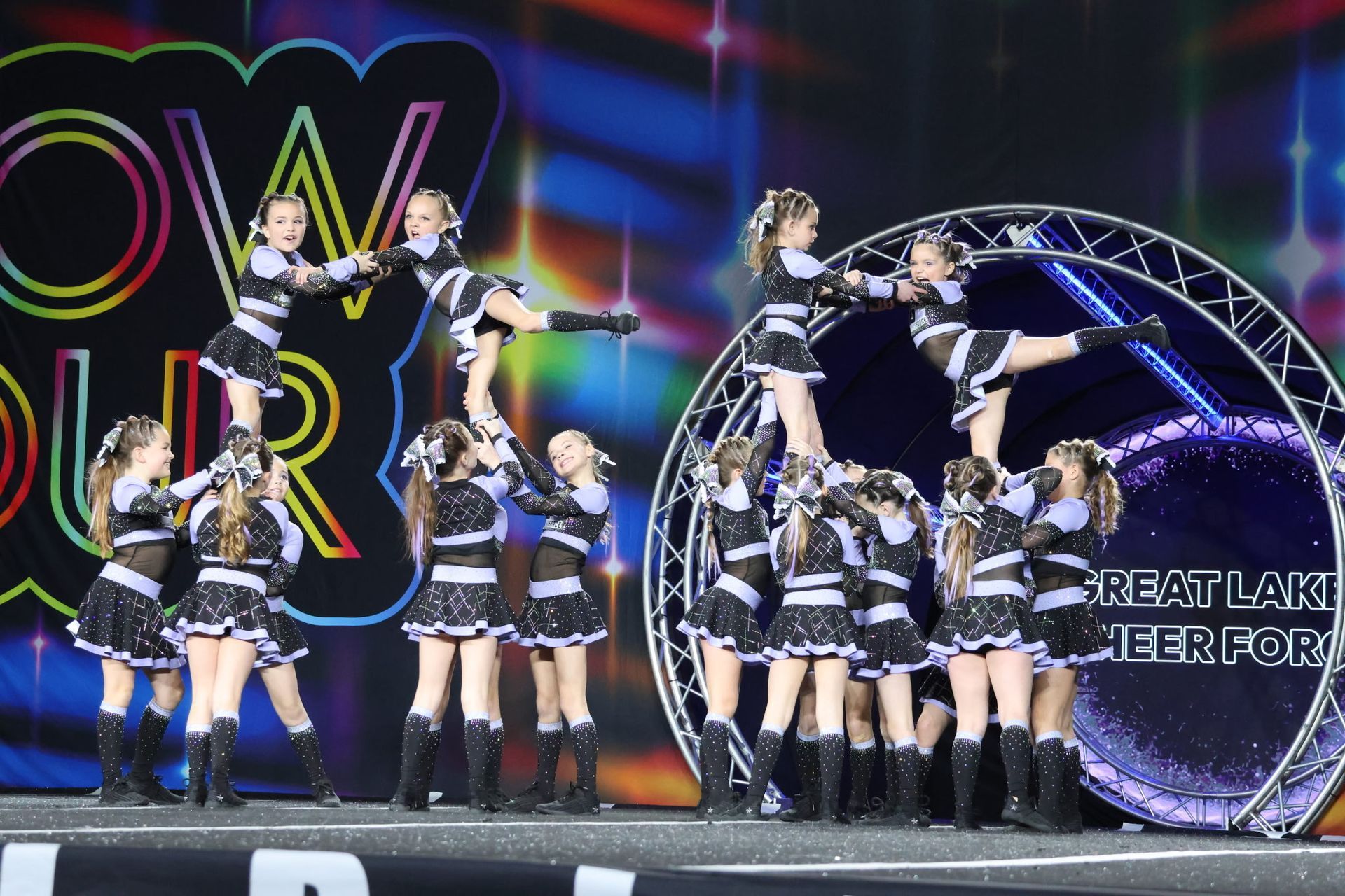 A group of cheerleaders are performing on a stage in front of a sign that says power
