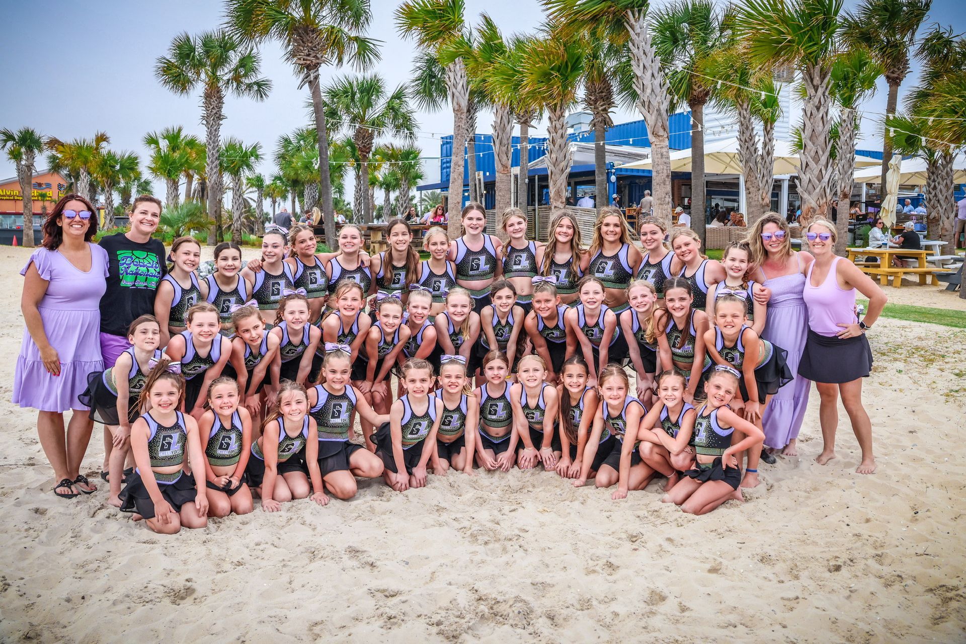 A group of children are posing for a picture on the beach.
