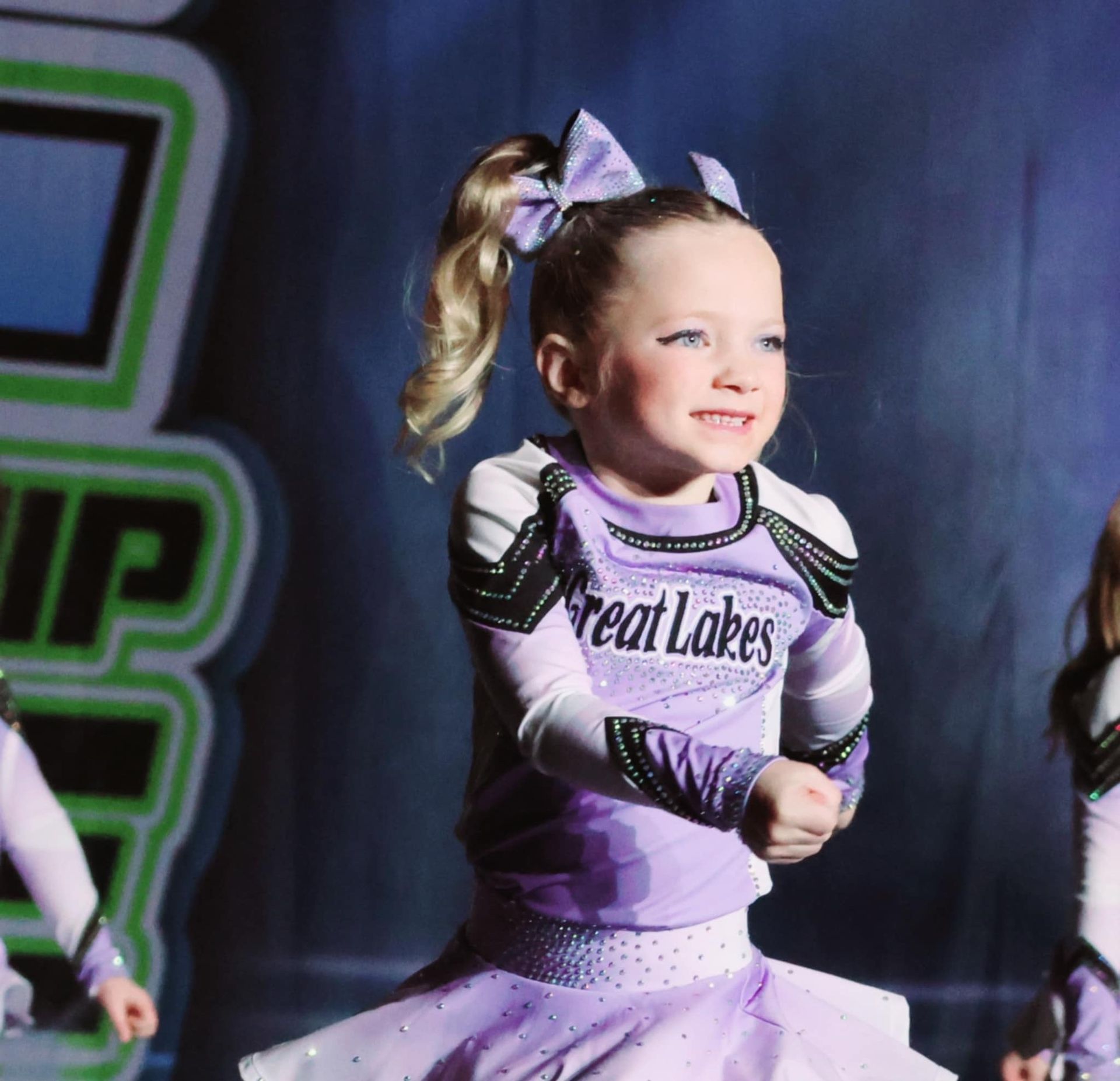 A little girl is wearing a purple cheerleading uniform that says great lakes
