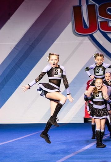 A cheerleader with the number 6 on her chest is jumping in the air