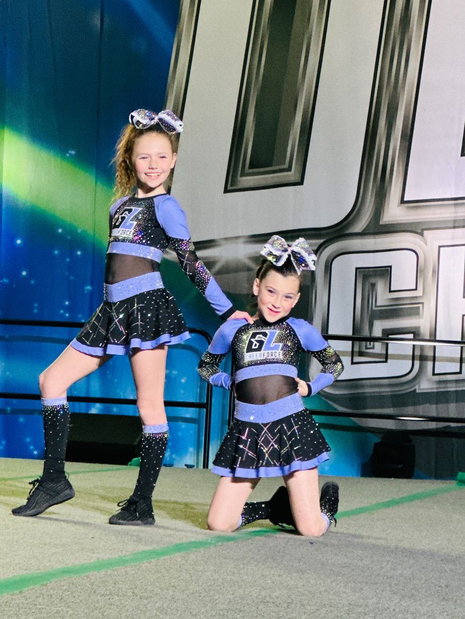 Two cheerleaders are posing for a picture on a stage