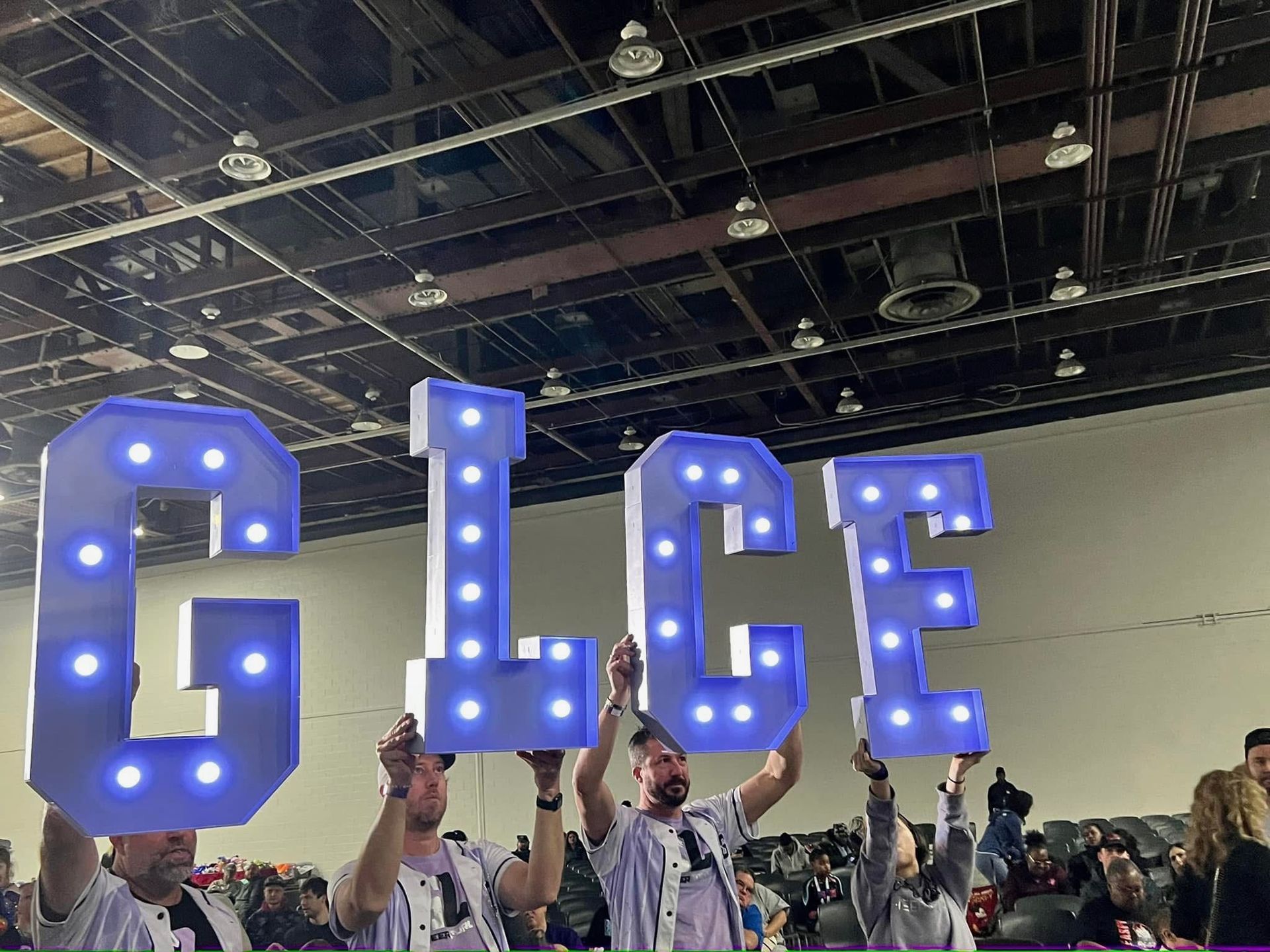 A group of people are holding up a sign that says GLCF