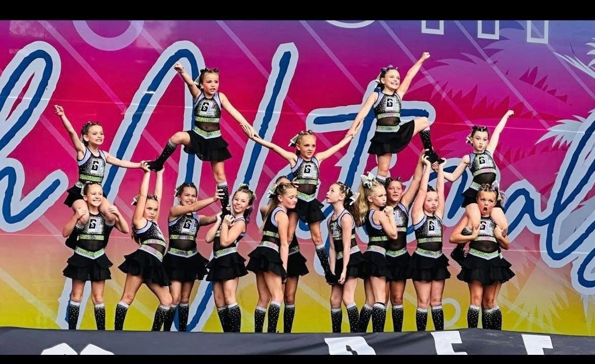 A group of young girls are performing a cheerleading routine on a stage.
