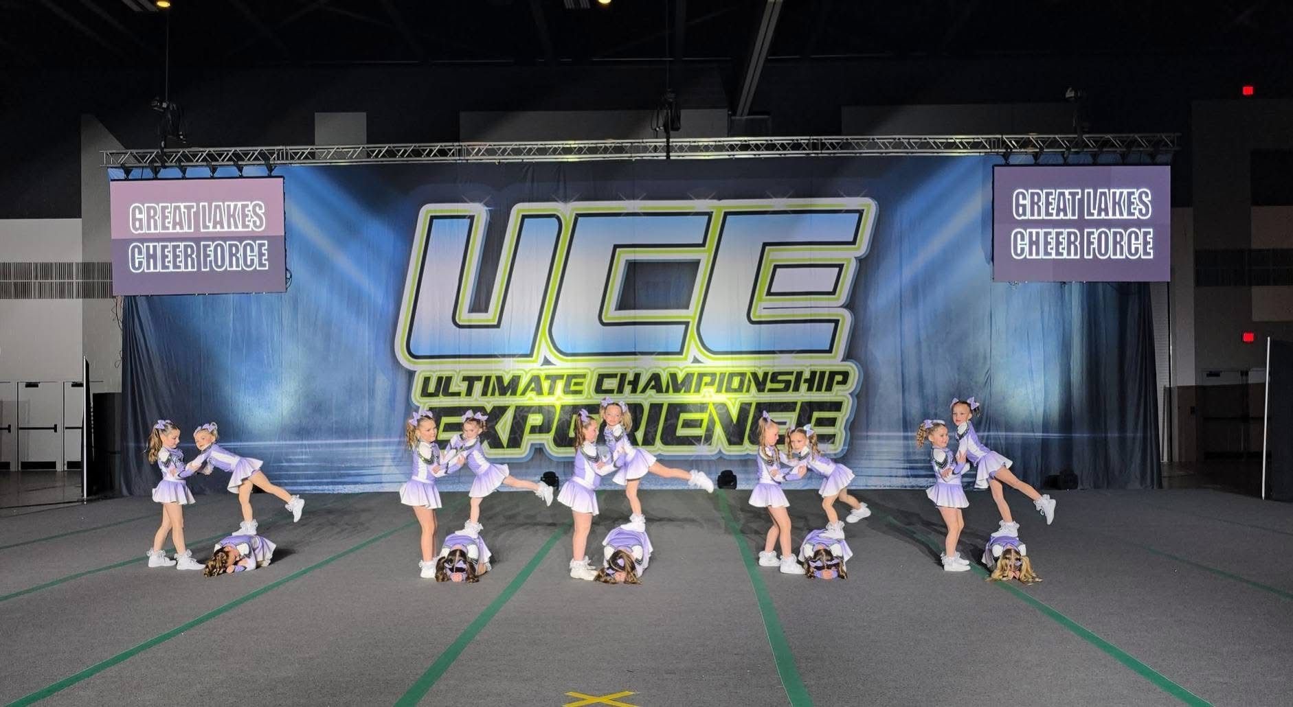 A group of cheerleaders are performing in front of a banner that says uce ultimate championship experience